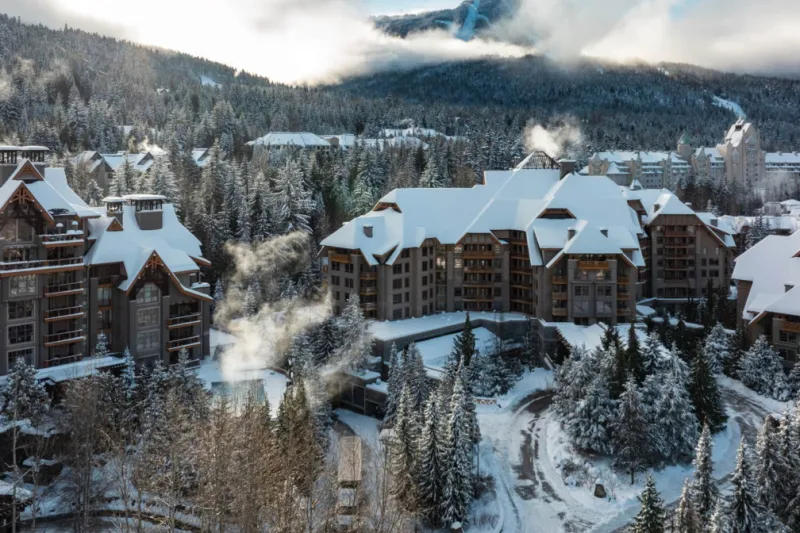 Four Seasons Resort Whistler under fresh snow, surrounded by evergreens in the Upper Village