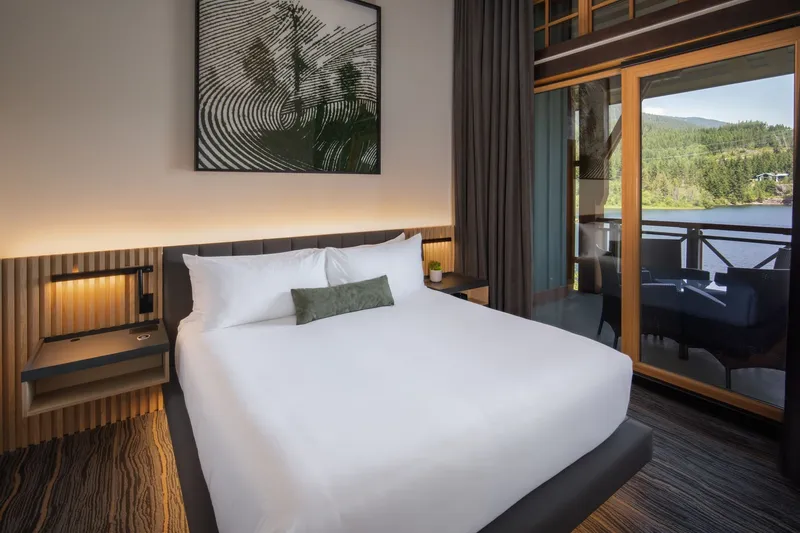A Nita Lake Lodge guest room with a balcony looking out over the lake and forest